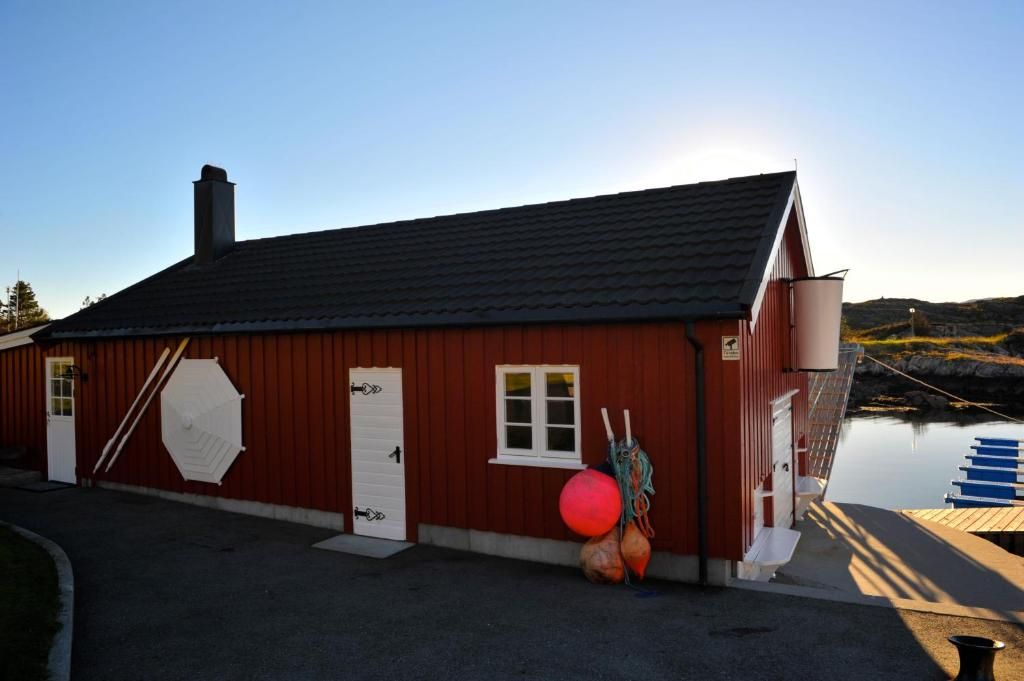 The on-site museum — a traditional red Norwegian boathouse with buoys on the dock at Ekkilsøy