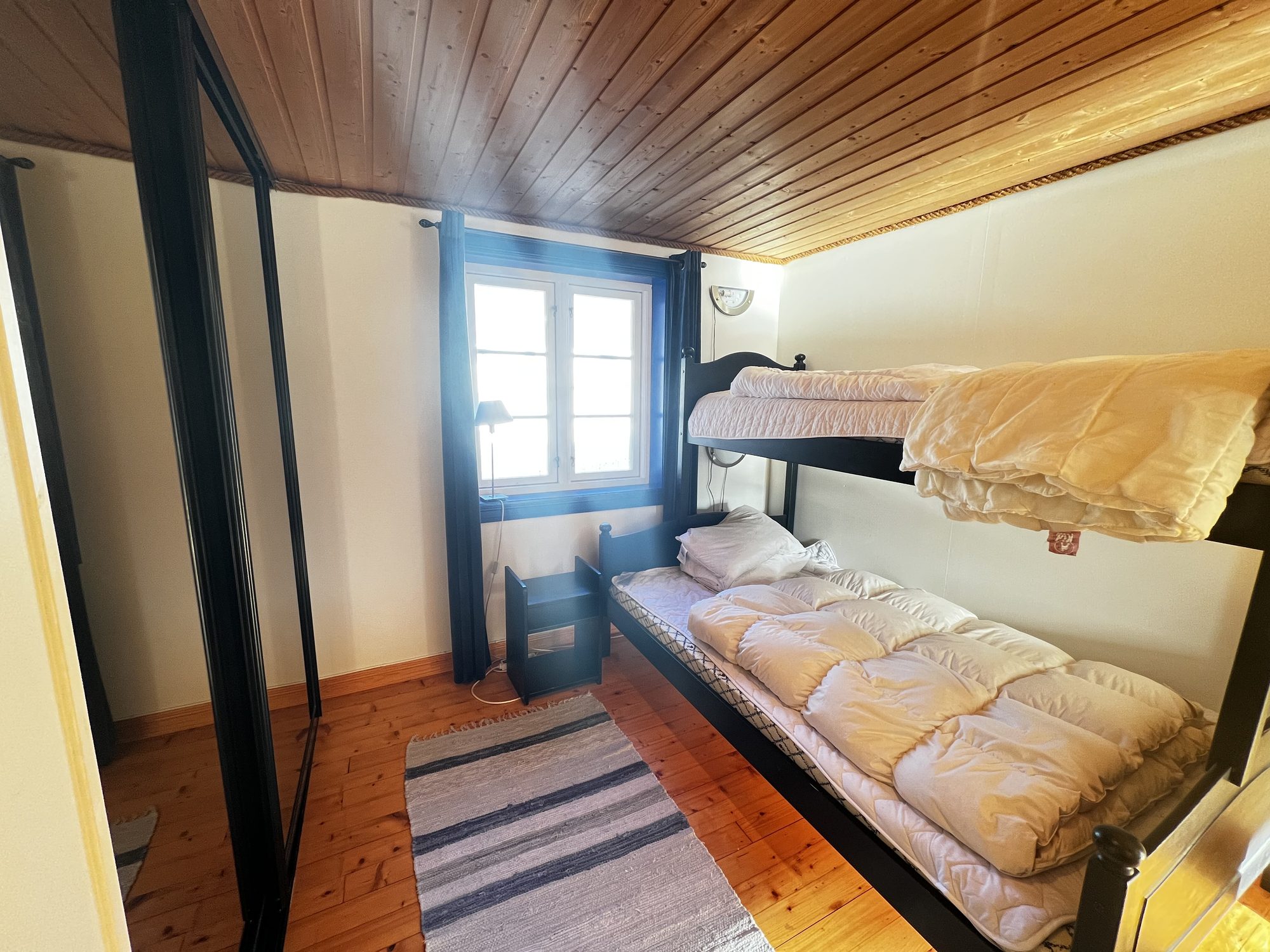 The Heritage — bunk bedroom with blue-framed window under the sloping ceiling