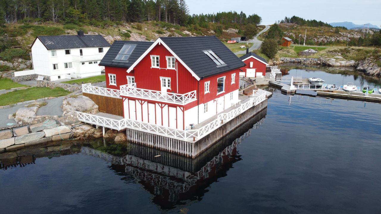 The Heritage — aerial view of the red coastal house on the water