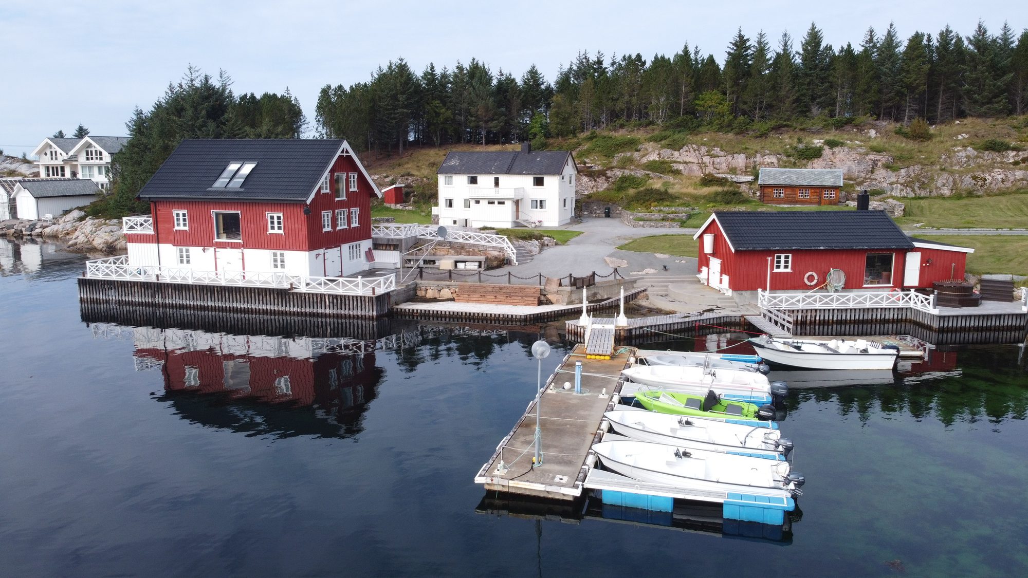 The Heritage — aerial view of the red coastal house, boathouse and floating dock