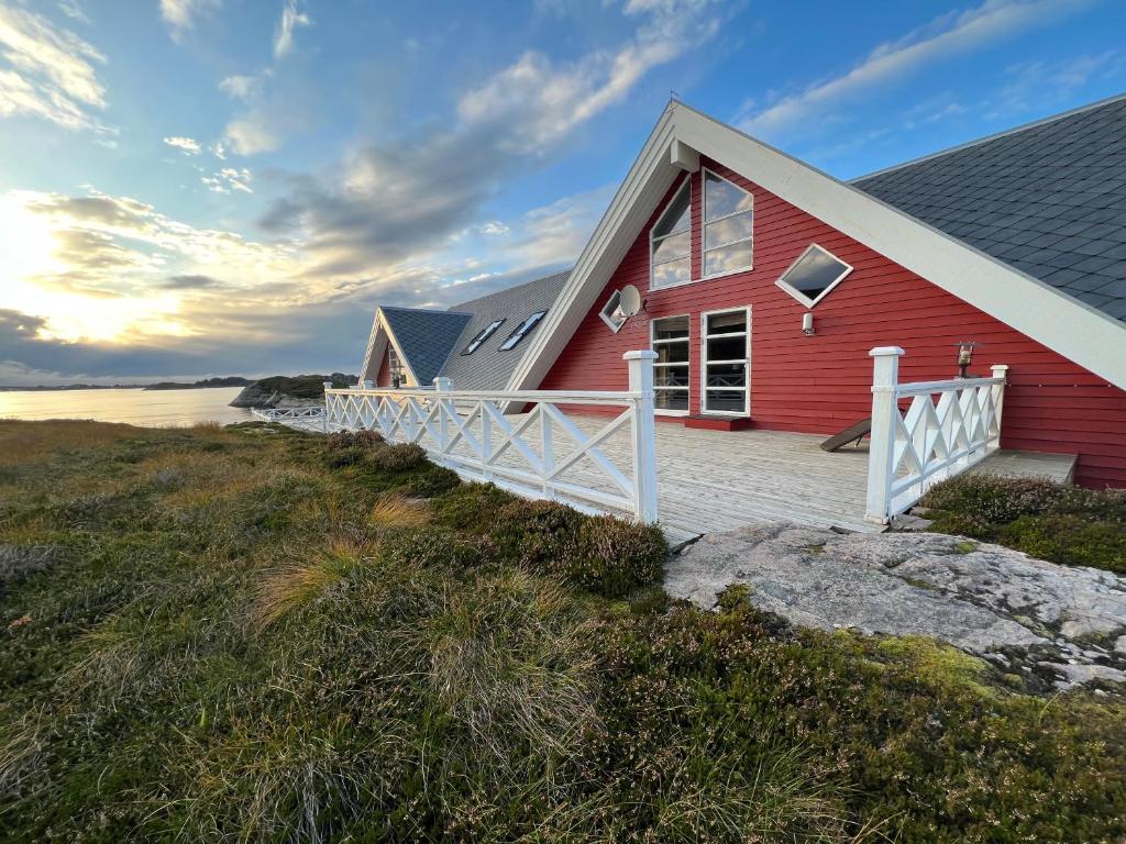 The red gable house with white terrace railings, seen from the rocky shoreline
