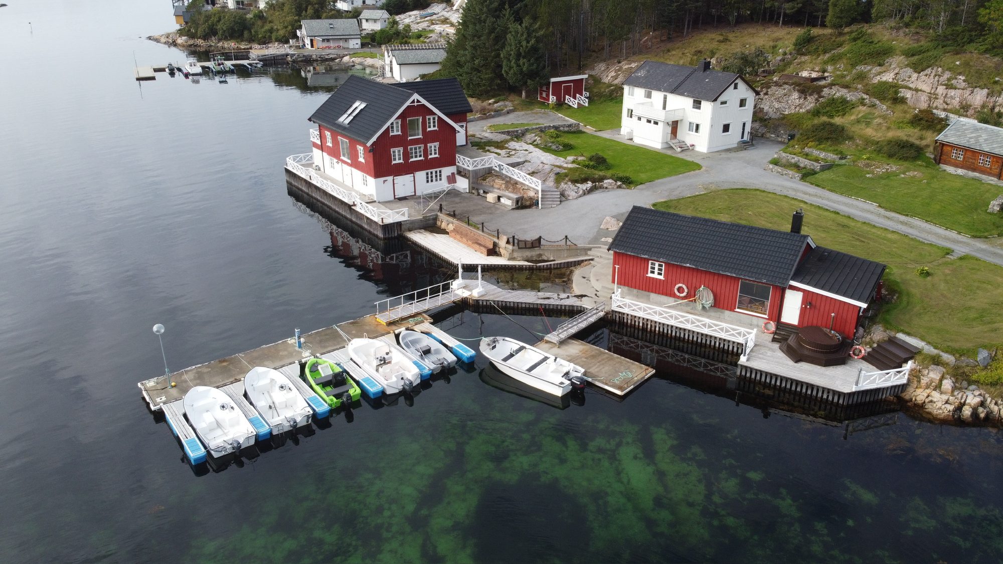Aerial view of the private quay with moored boats beside the red houses on Ekkilsøy