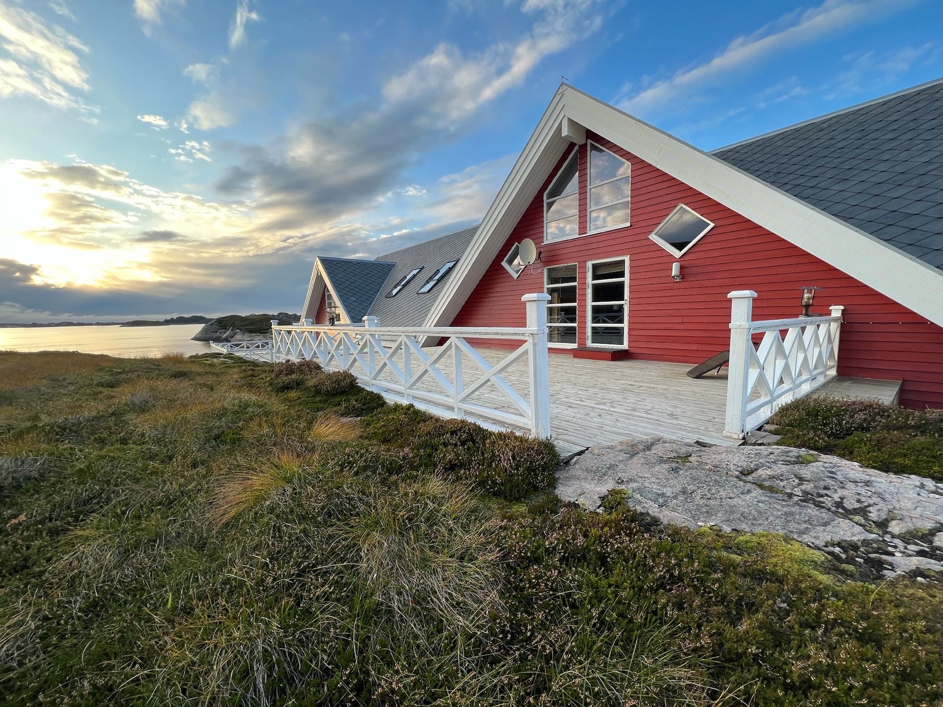 The red gable of the house with white terrace railings at sunset on Ekkilsøy