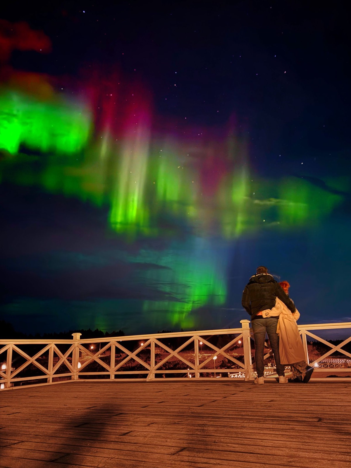 Aurora borealis in vivid green and purple above the coastline on a clear winter night
