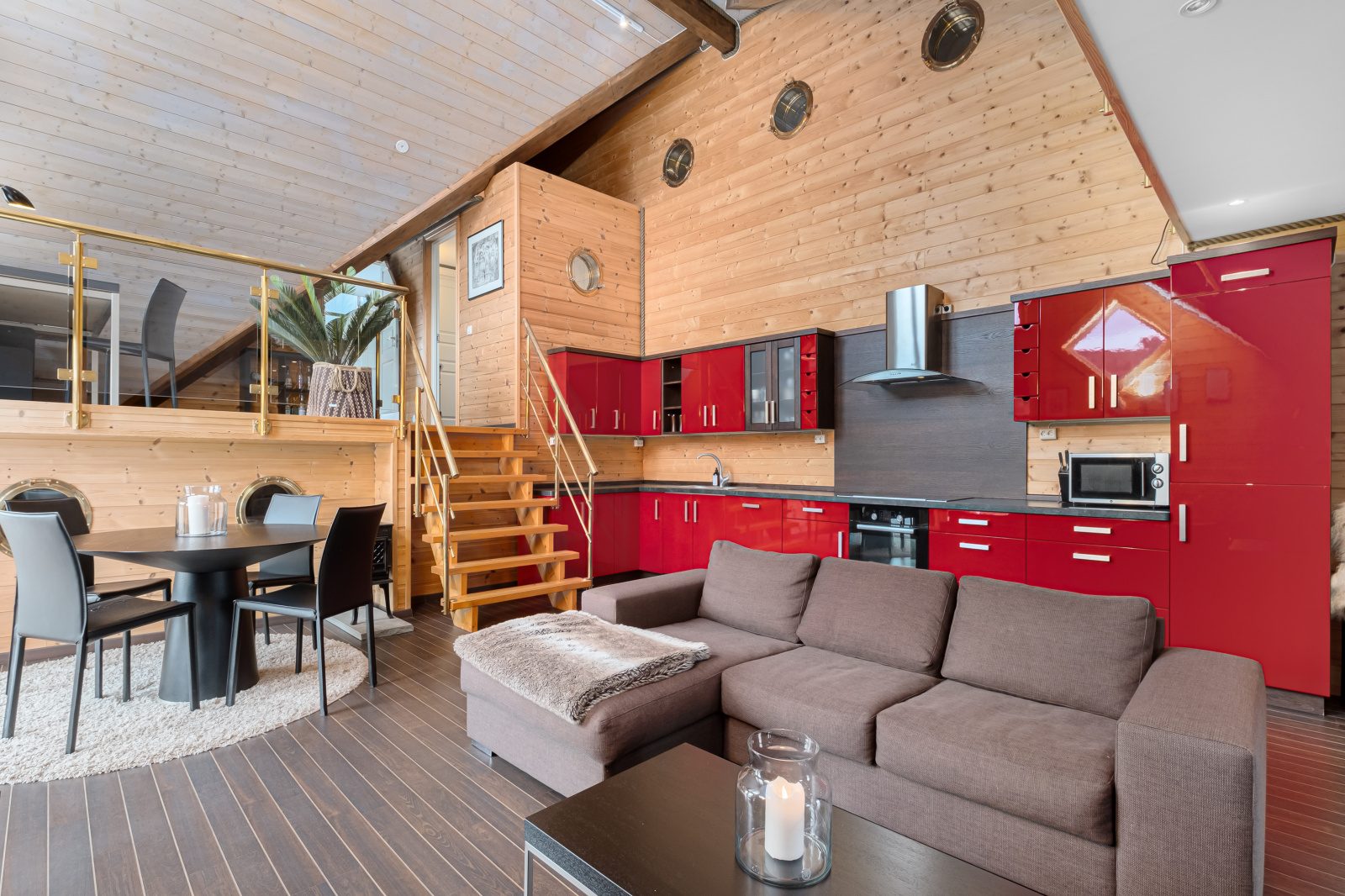 Aurora Suite — living area with corner sofa, dining table and red kitchen