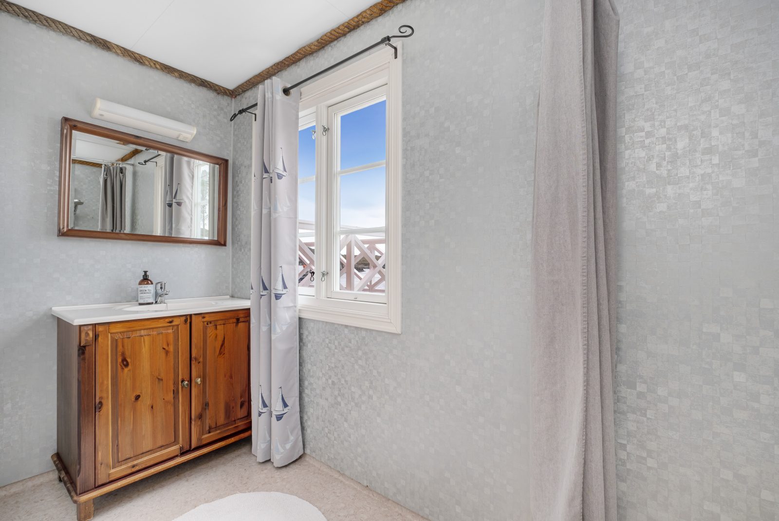 The North Loft — bathroom with wooden vanity and sailboat curtains