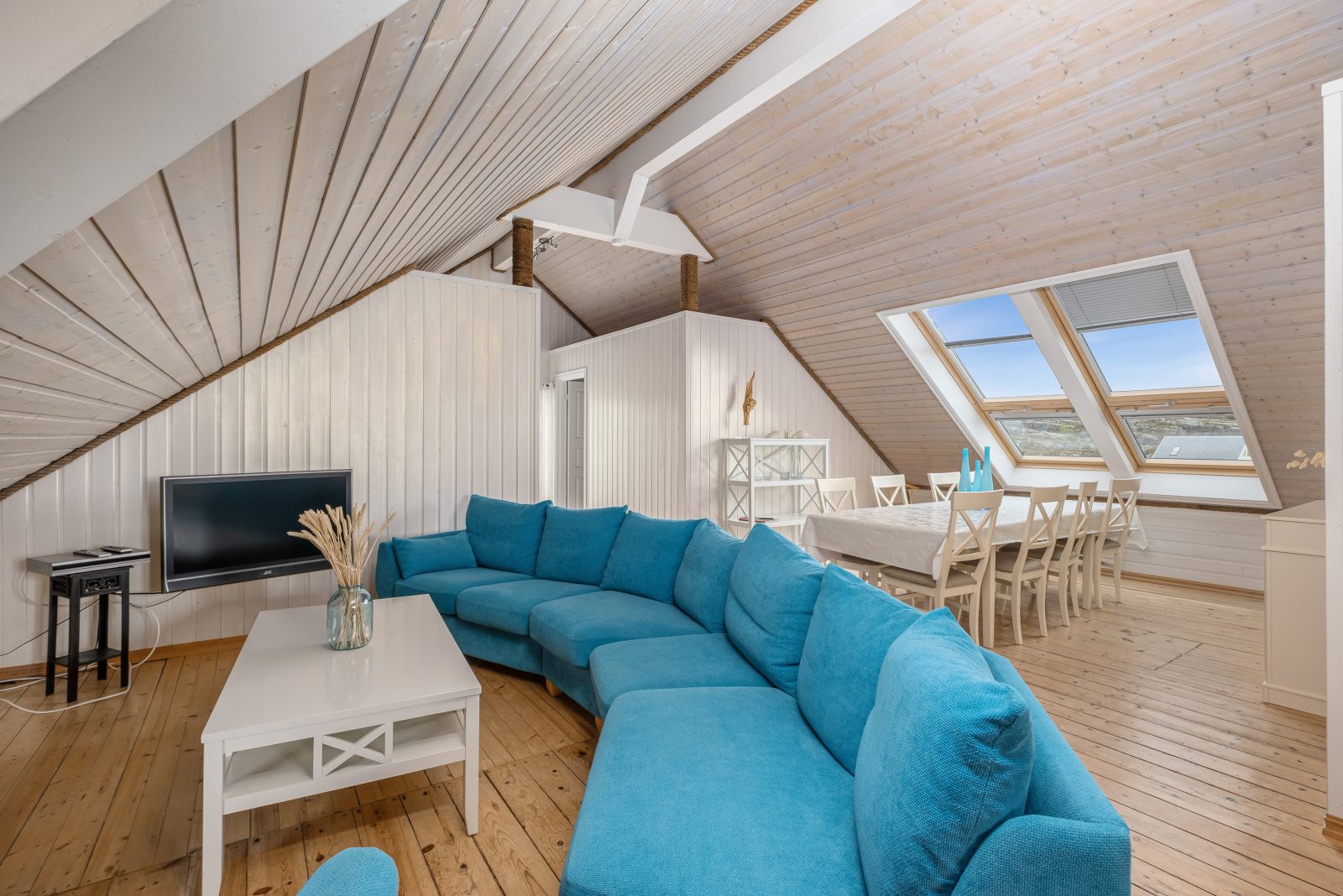 The North Loft — open living and dining with skylights and turquoise sofa