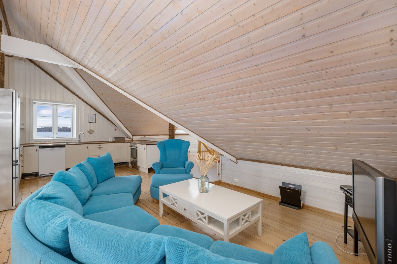 The North Loft — living area with turquoise sofa and open kitchen behind
